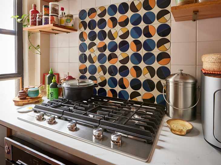 Kitchen stovetop with circular tile backsplash.