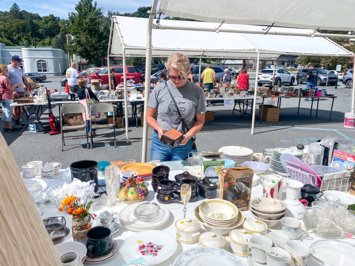 Woman browsing tablewares at outdoor market.