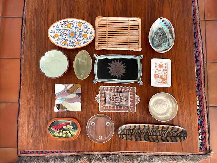 A variety of decorative plates and trays arranged on a wooden table, featuring different colors and designs.