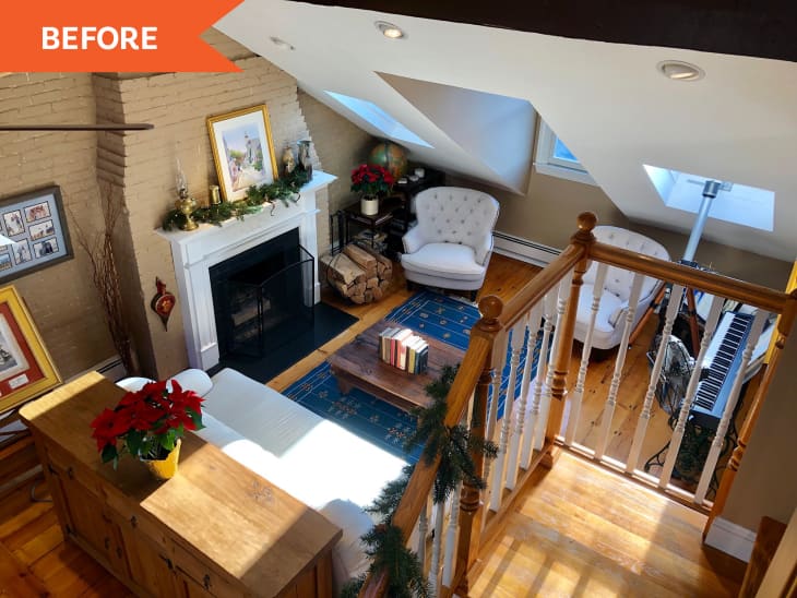Cozy attic living room with fireplace, white armchairs, blue rug, and holiday decor.
