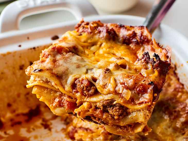 Slice of lasagna being lifted out of pan of lasagna