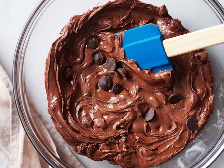 someone is mixing chocolate chips in the dough of the flourless chocolate brownie cookes
