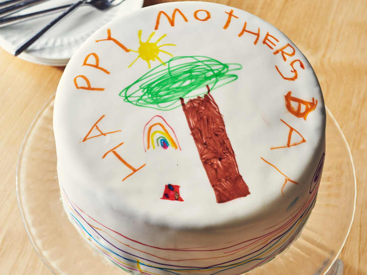 someone is drawing on a happy mothers day cake with edible markers