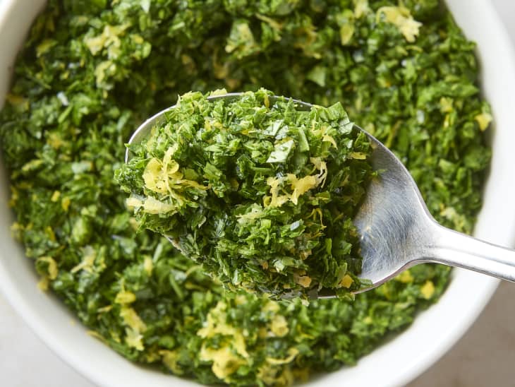 overhead shot of gremolata in a small white bowl, with some on the spoon