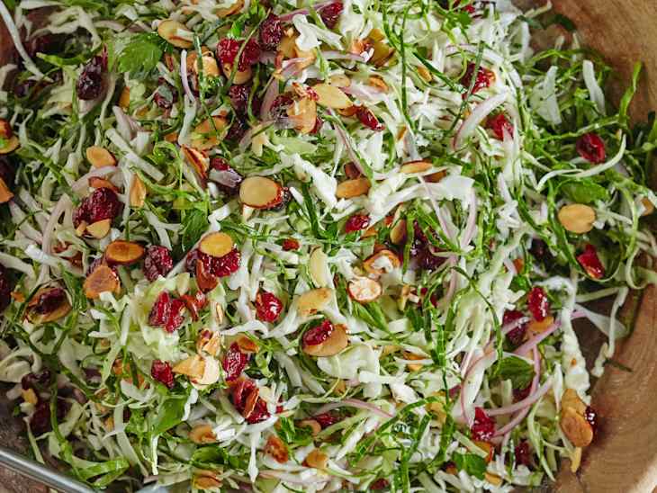 A bowl of Thanksgiving slaw with sliced almonds and cranberries