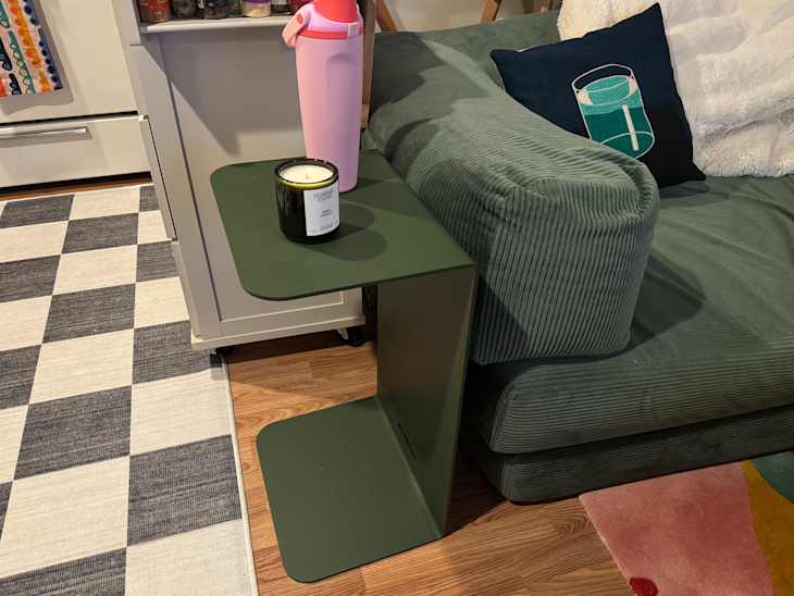 Haworth side table topped with candle and water bottle beside sofa.