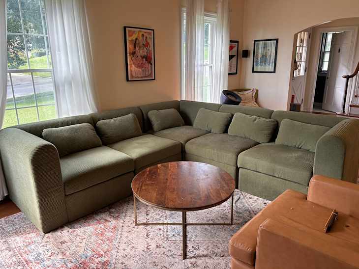 Cozy living room featuring a green sectional sofa, round wooden coffee table, and a patterned area rug.