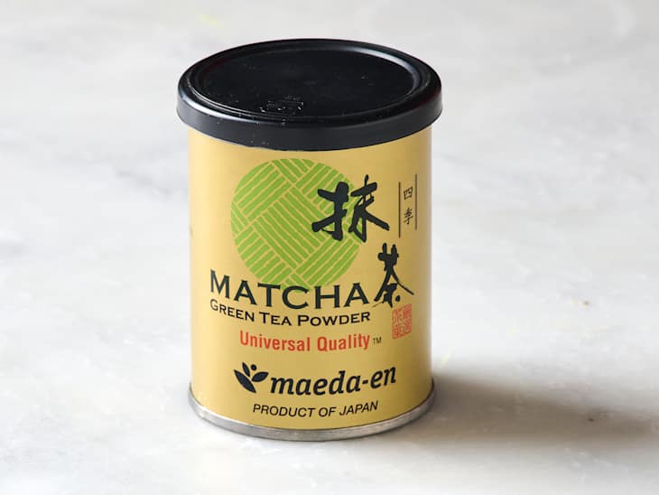 Canister of matcha green tea powder with a gold label, featuring a green design and black text.