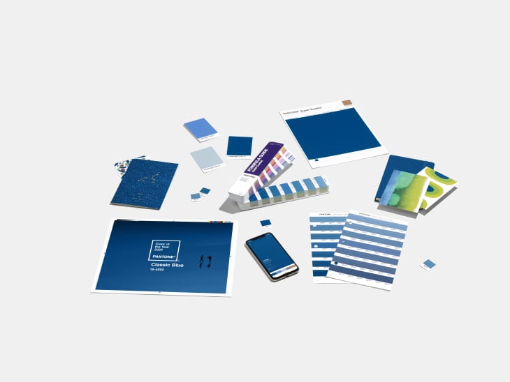 Pantone Classic Blue color swatches, fan deck, and smartphone on a light surface.