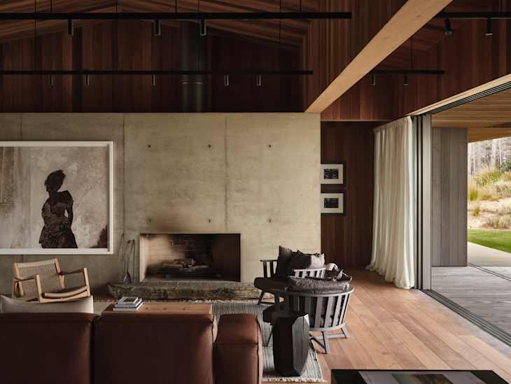 Modern living room with a concrete wall, wooden accents, a fireplace, and large sliding doors opening to an outdoor area.
