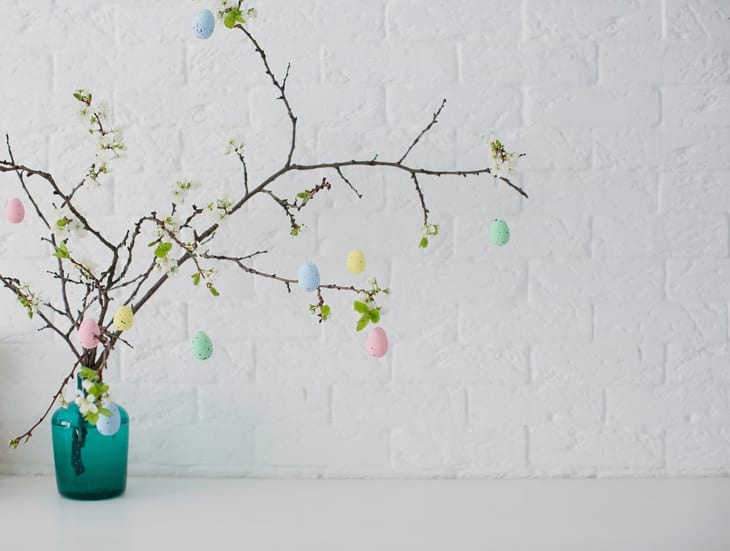 Easter tree in blue vase with colorful eggs on a white background