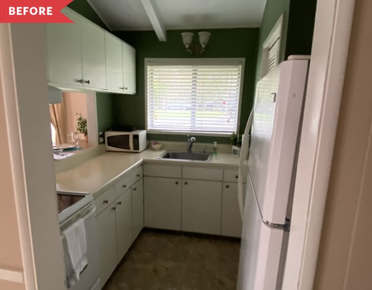Small kitchen with green walls, white cabinets, a microwave, and a window above the sink.