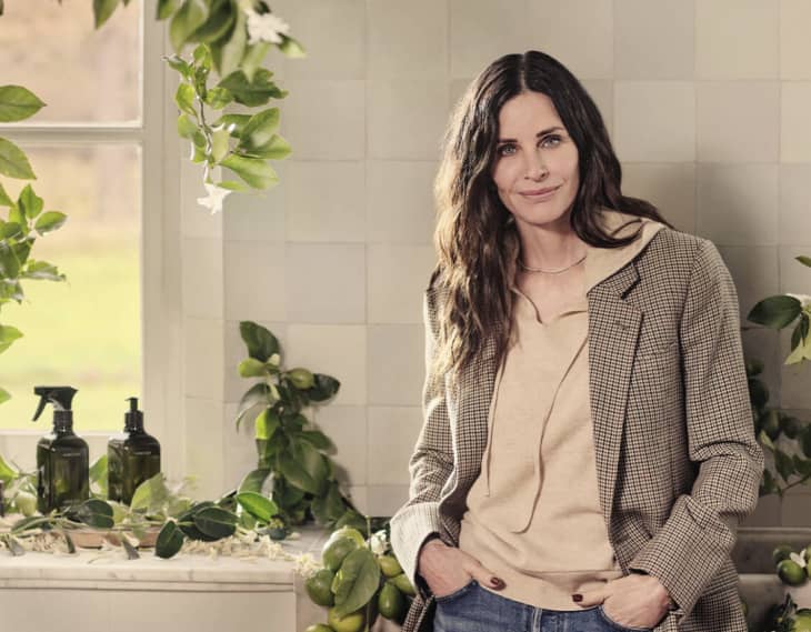 Courteney Cox in a kitchen with leaves and cleaning products