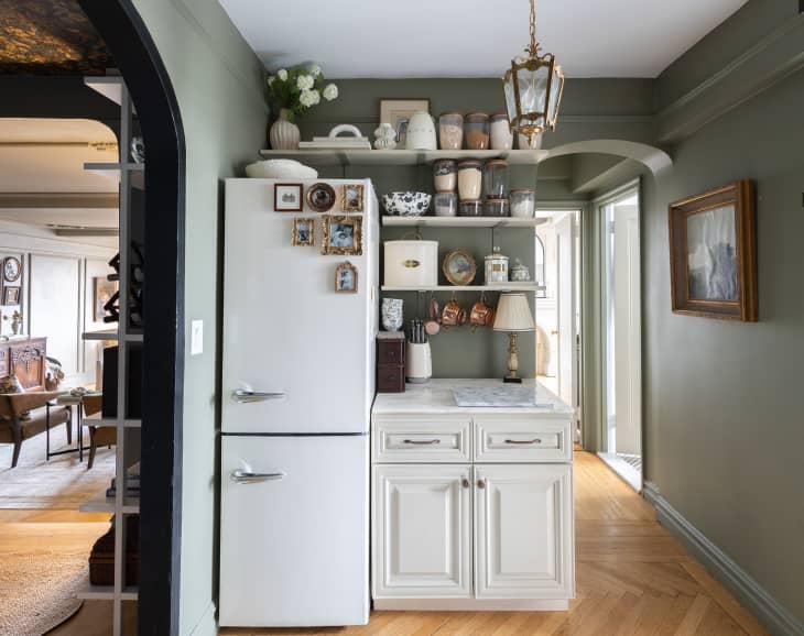 Kitchen with grey-green walls, open shelving, hardwood floors and hexagonal tile