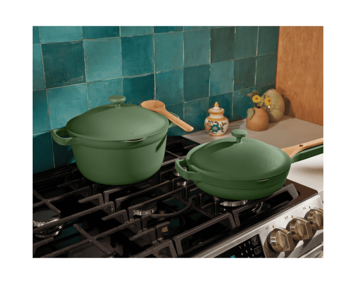 Green Dutch oven and skillet on a stove with teal tile backsplash and decorative kitchen items.