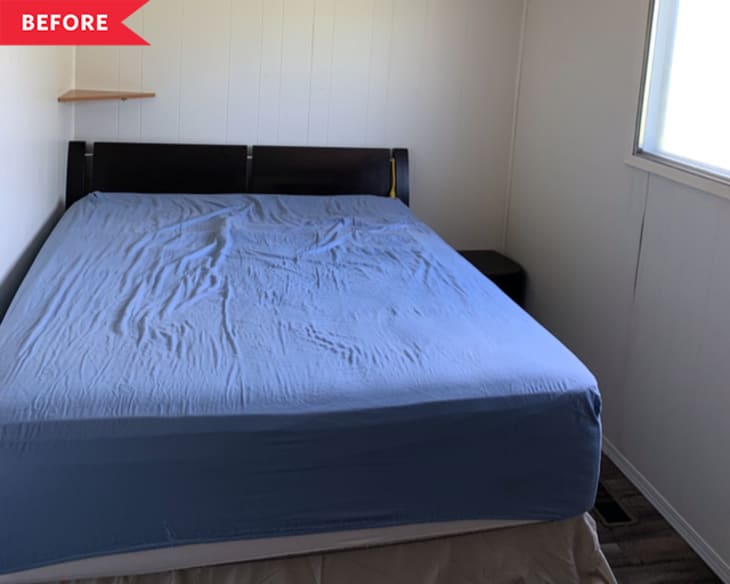 Small bedroom with a bed covered in a blue sheet, dark headboard, and a small wall shelf.