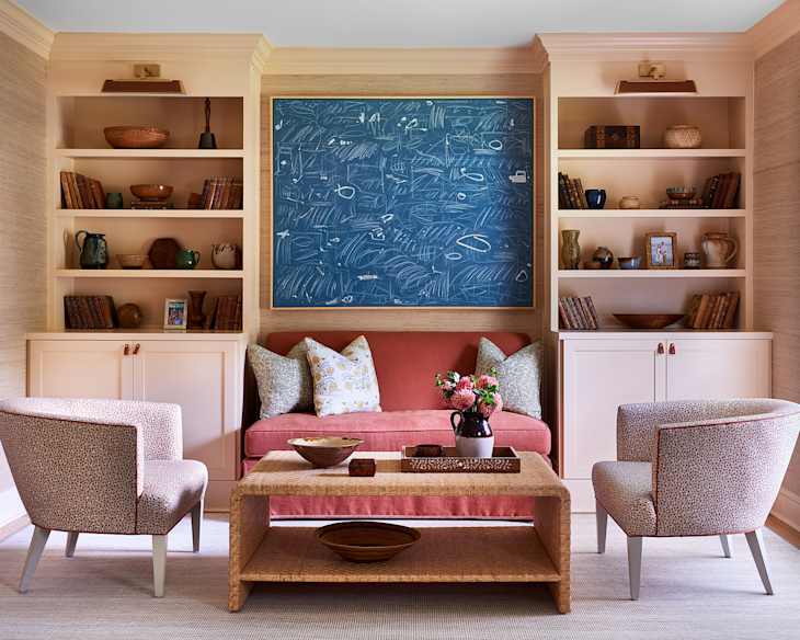Room with different shades of blush and other warm colors with large piece of centered art and built in shelves