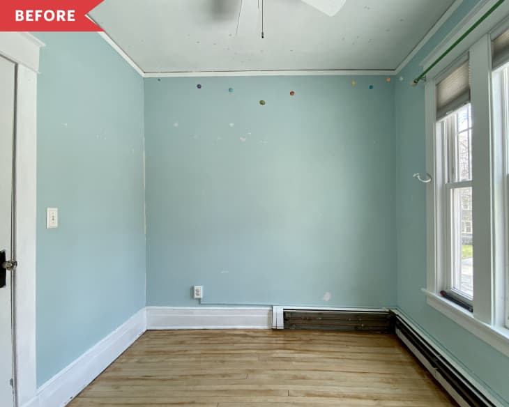 Empty room with light blue walls, hardwood floor, and three windows on the right.