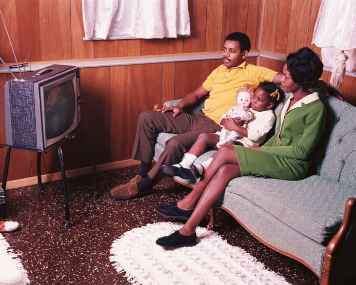 charming retro woman sitting on vintage suitcase and tv set while