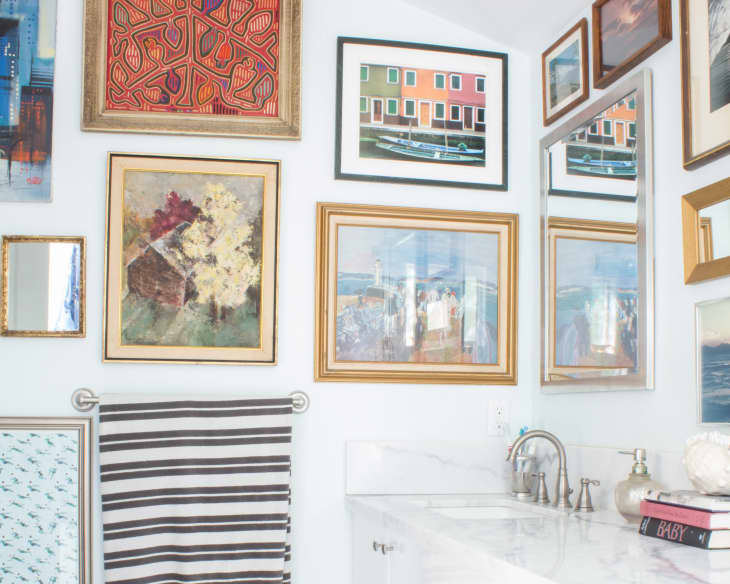 white bathroom with lots of framed art on the walls