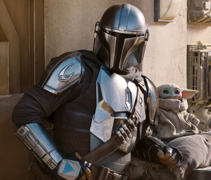 Armored figure with helmet and small creature with large ears sitting on a ledge in a desert setting.