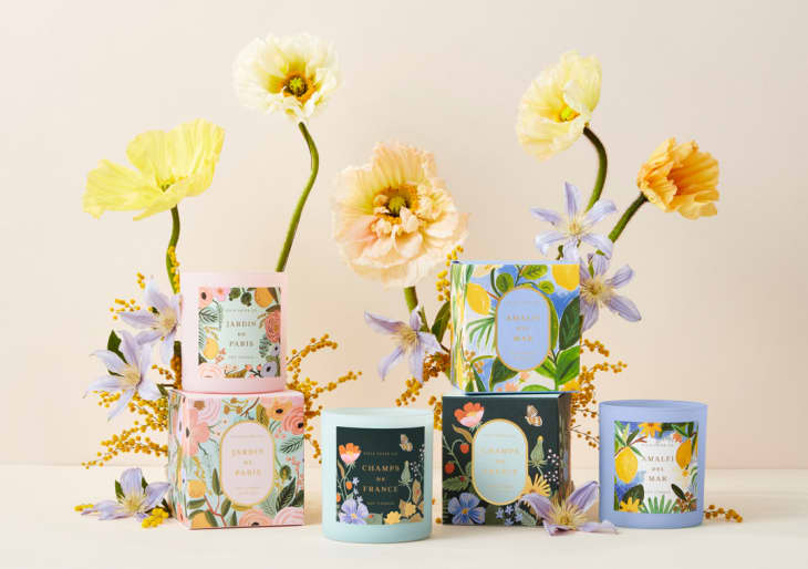 Stack of botanical-scented candles with flowers beside them