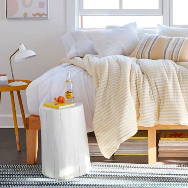 Bed with yellow bedding and two small side tables next to it