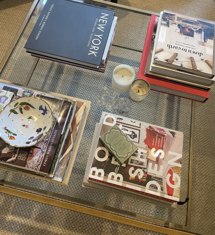 Gold frame glass square coffee table styled with books and candles and trinkets