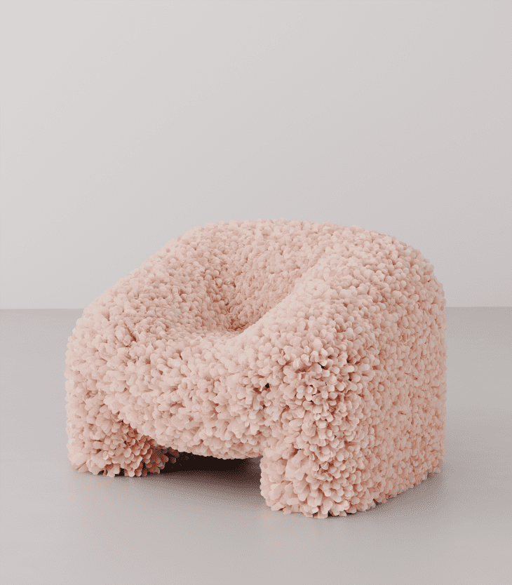 Curved armchair with textured pink floral upholstery on a gray floor.