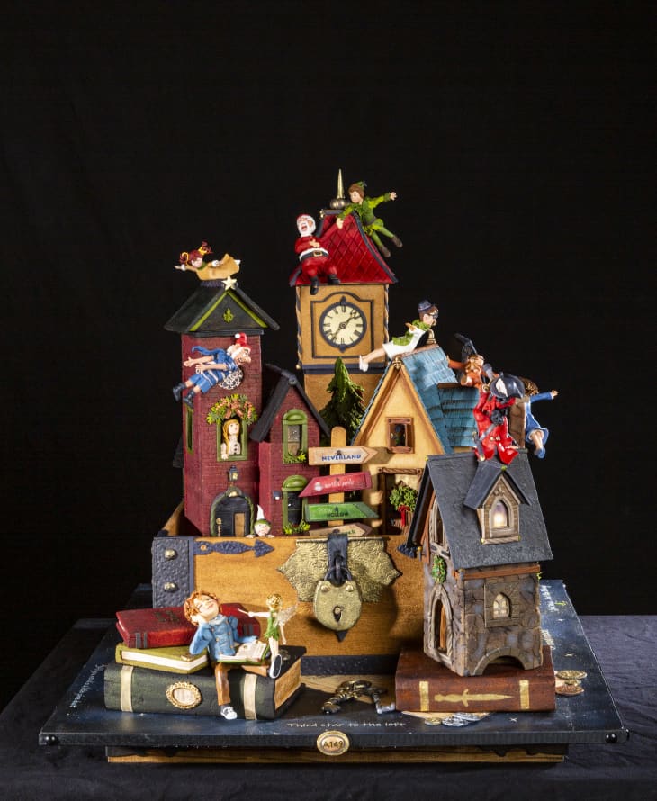 Whimsical Peter Pan-themed diorama with colorful houses, clock tower, and characters in playful poses.