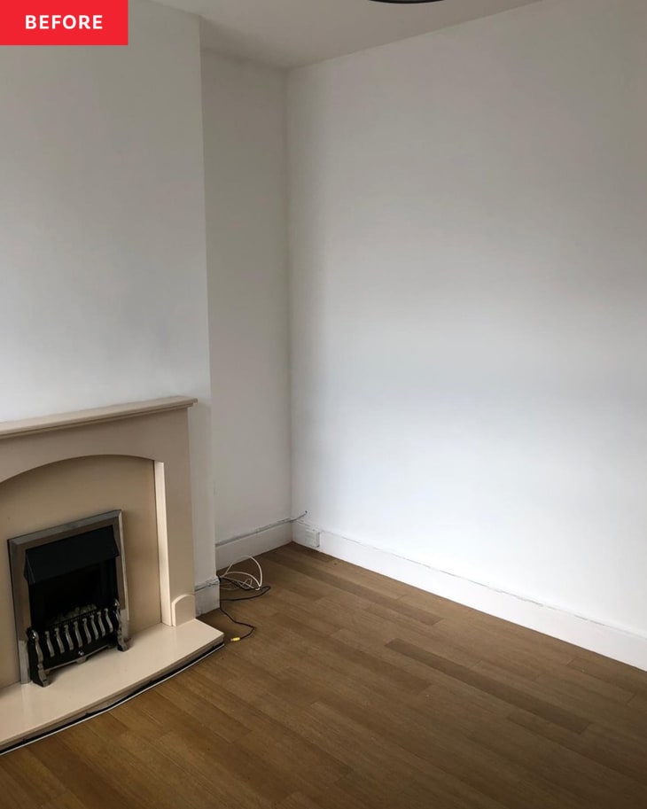 Empty room with a beige fireplace, white walls, and wooden floor.