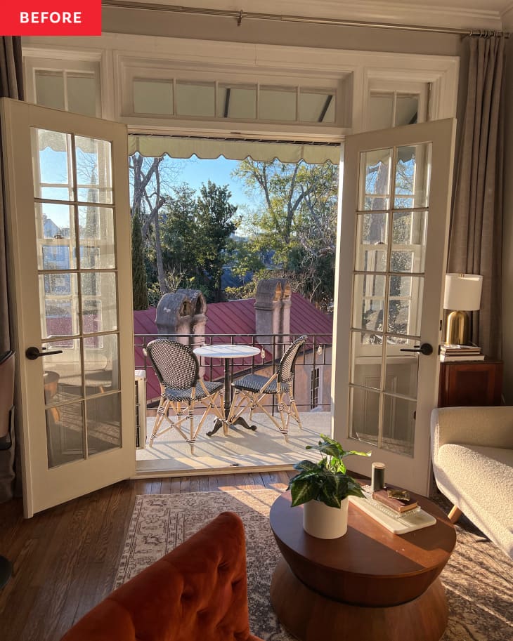 view from living room out to small terrace before terrace makeover. Terrace floor is white painted concrete, small white round table with 2 woven chairs, no decor