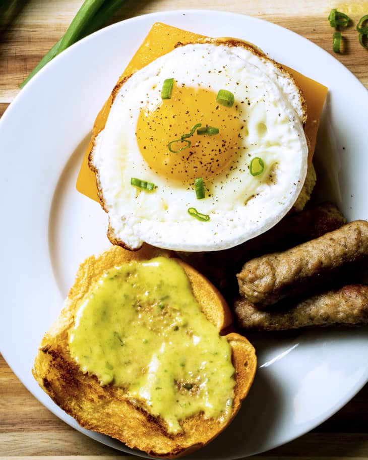 open egg sandwich with round fried egg, toast, and sausage