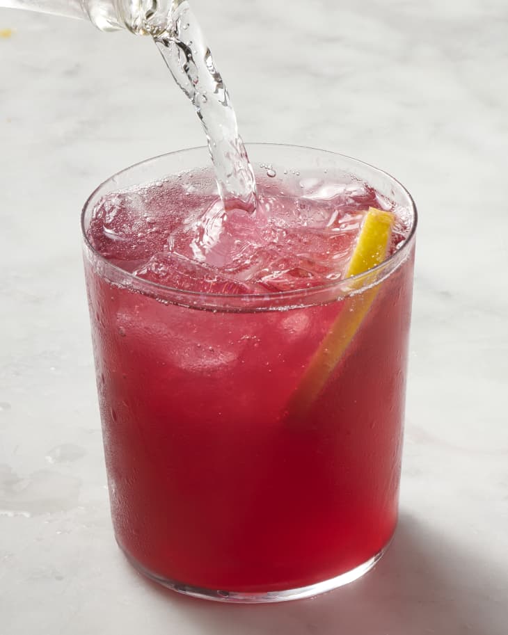 A photo of a glass of red tinto de verano cocktail getting seltzer poured in.