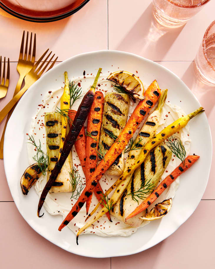 grilled yellow and orange carrots on a plate of labneh with herbs