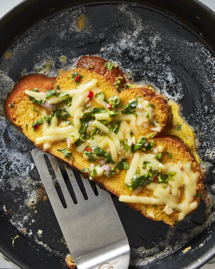 Overhead photo of Bombay Toast cooking in a skillet in butter. Metal spatula underneath slice