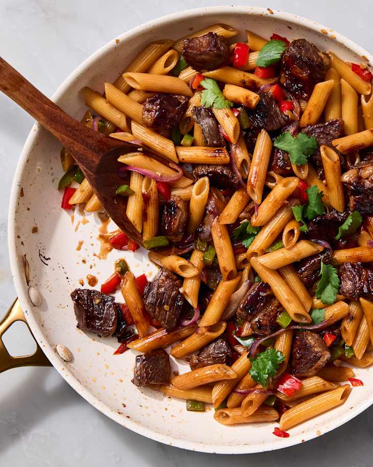 overhead shot of shaking beef with pasta in a pan