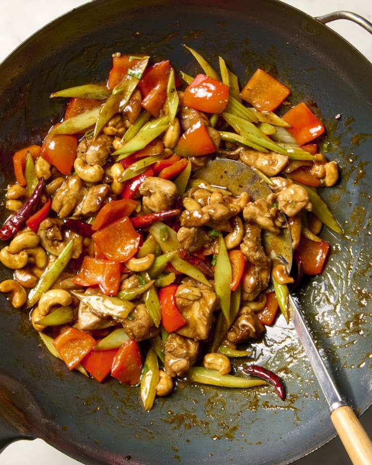 close up shot of cashew chicken in a wok, with a serving spoon