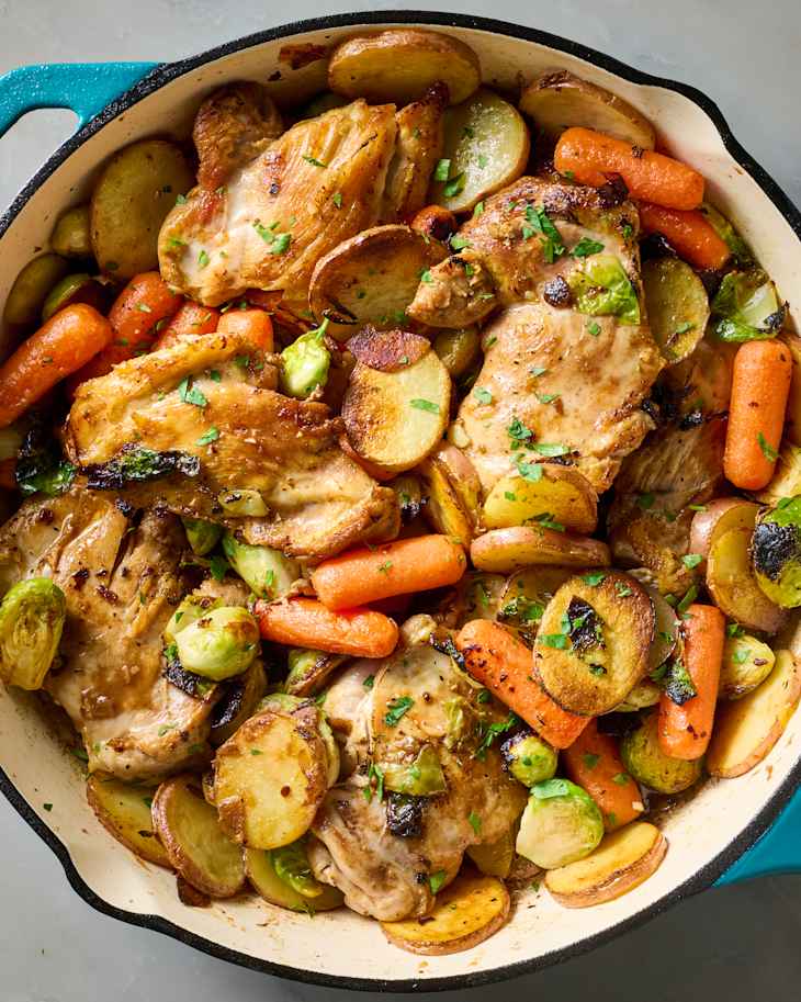 overhead shot of balsamic chicken, carrots and potatoes in a blue pan