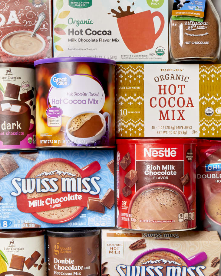Overhead shot of an assortment of hot cocoa packaging, like swiss miss, lake champlain, trader joes, great value and nestle.