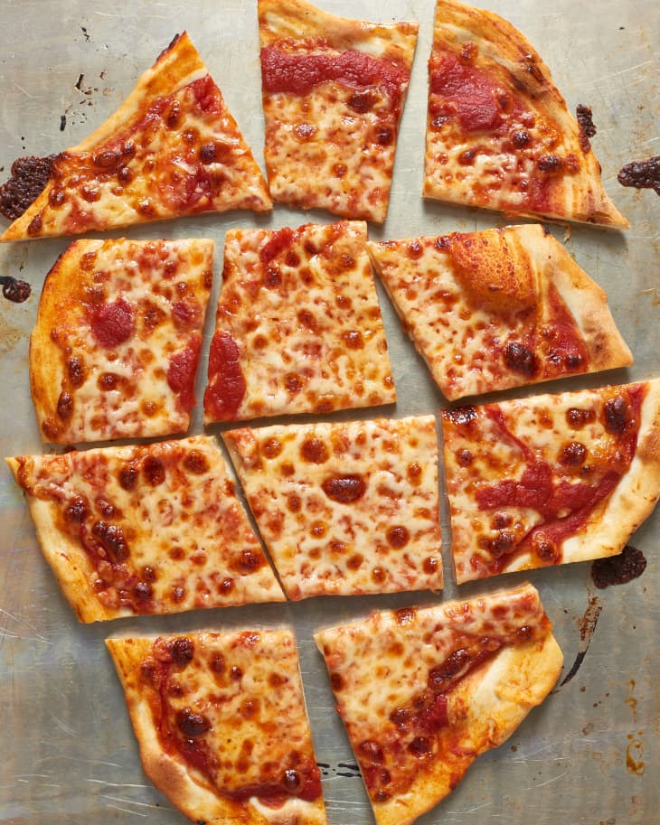 Square-cut cheese pizza slices on a metal baking sheet.