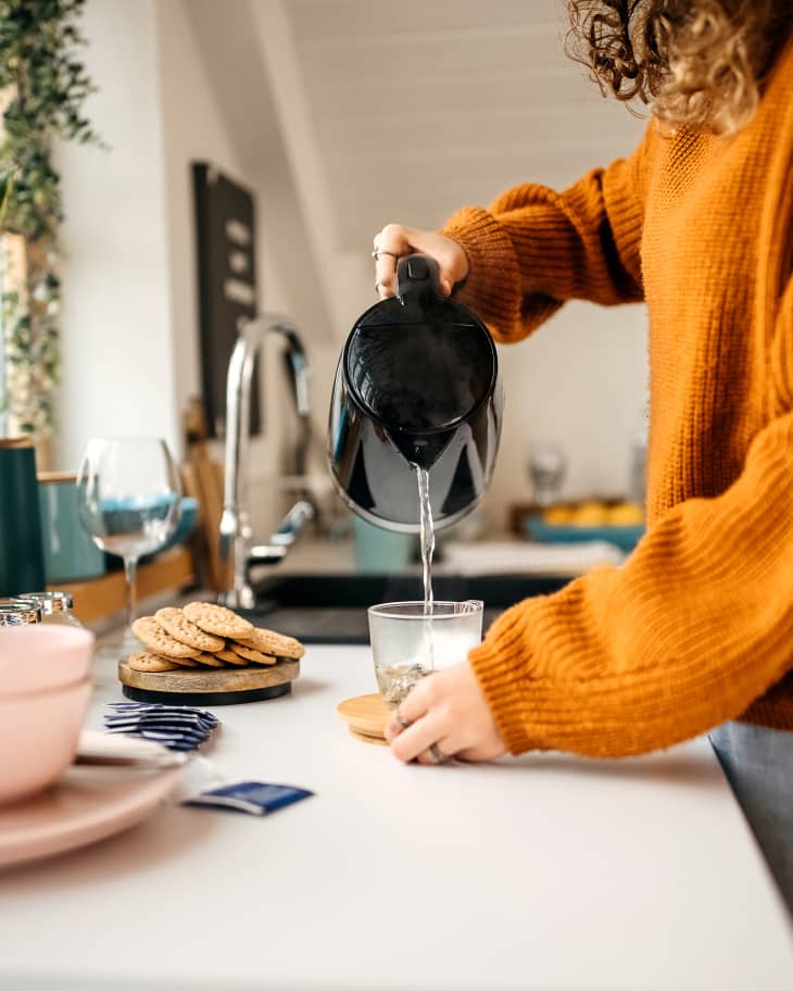 Young woman making herself some tea in her small kitchen at home