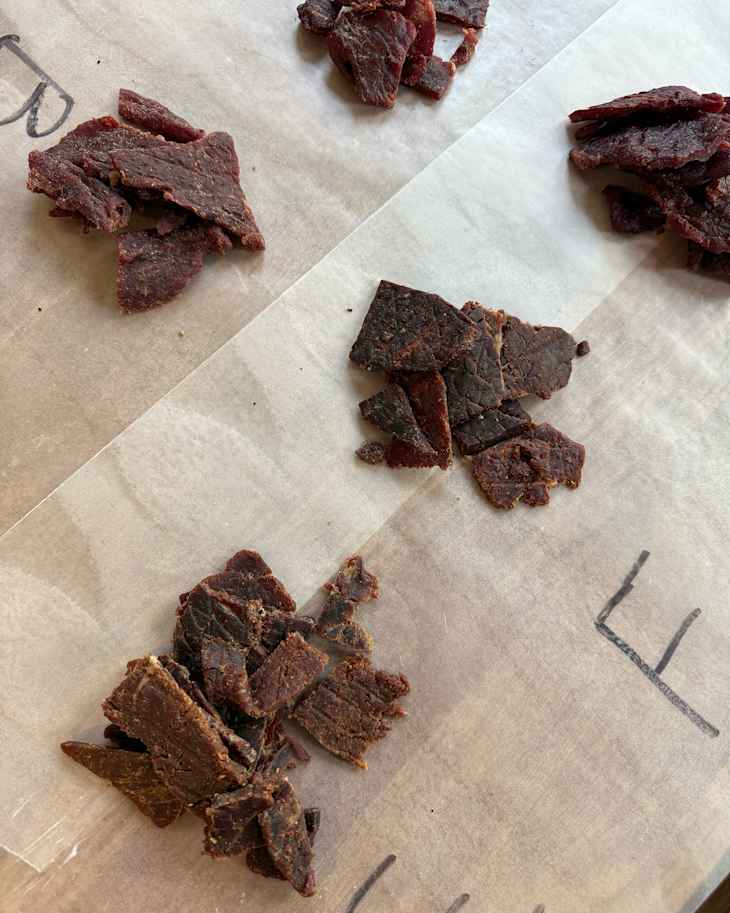 Various beef jerky brands on wax paper for taste test.