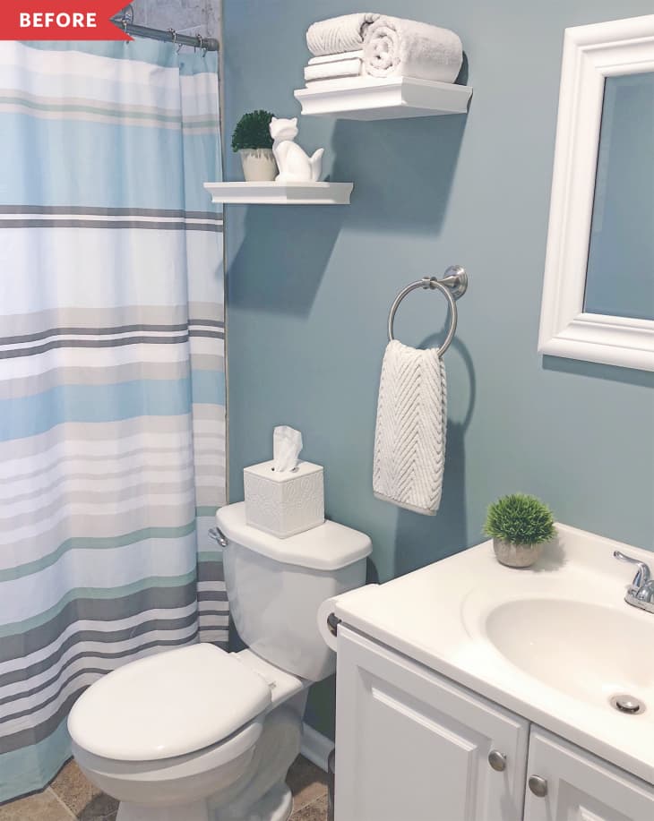 Small bathroom with blue walls, striped shower curtain, white shelves, towels, and decorative plant.
