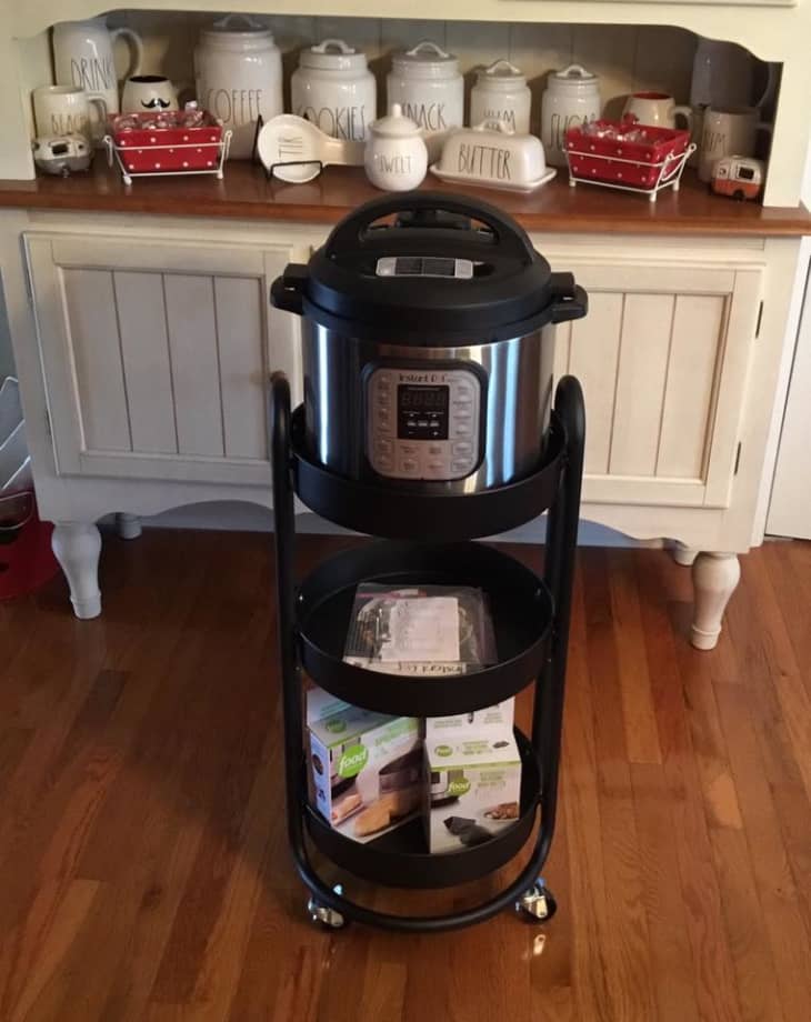 Instant Pot on a black rolling cart with kitchen canisters labeled coffee, cookies, snack, and sugar on a wooden shelf.
