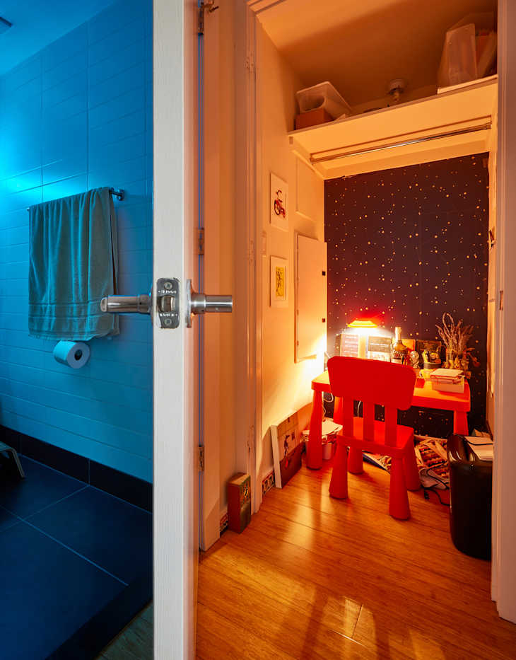Lamp and decor on red desk with chair in wallpapered nook.