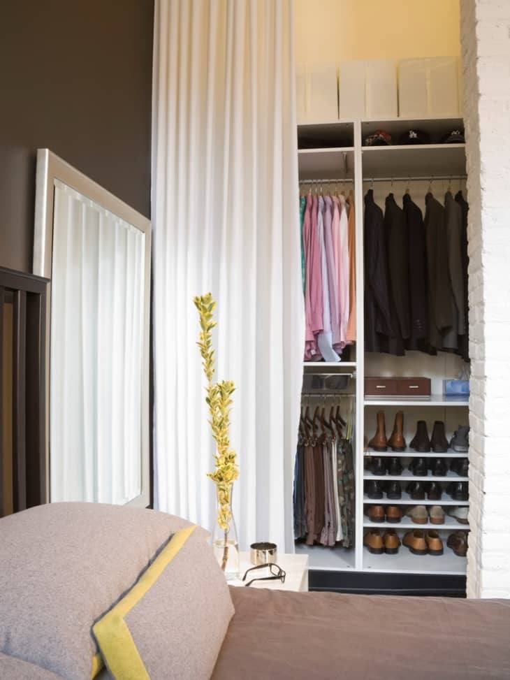 A long white curtain hides a closet since there are no closet doors