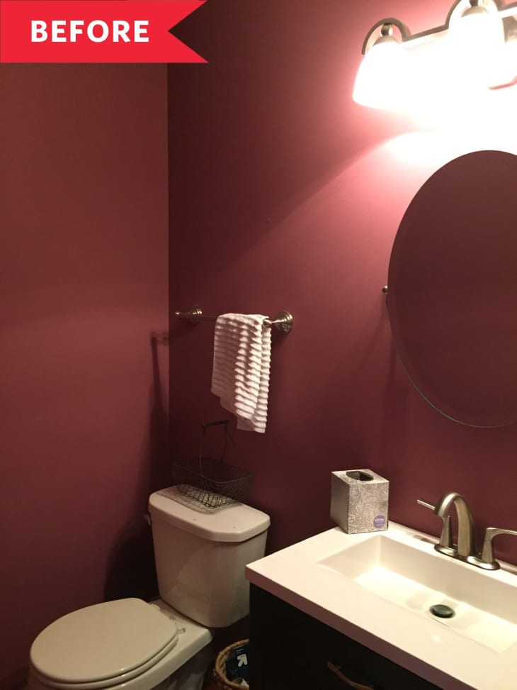 Small bathroom with maroon walls, oval mirror, white sink, and toilet.