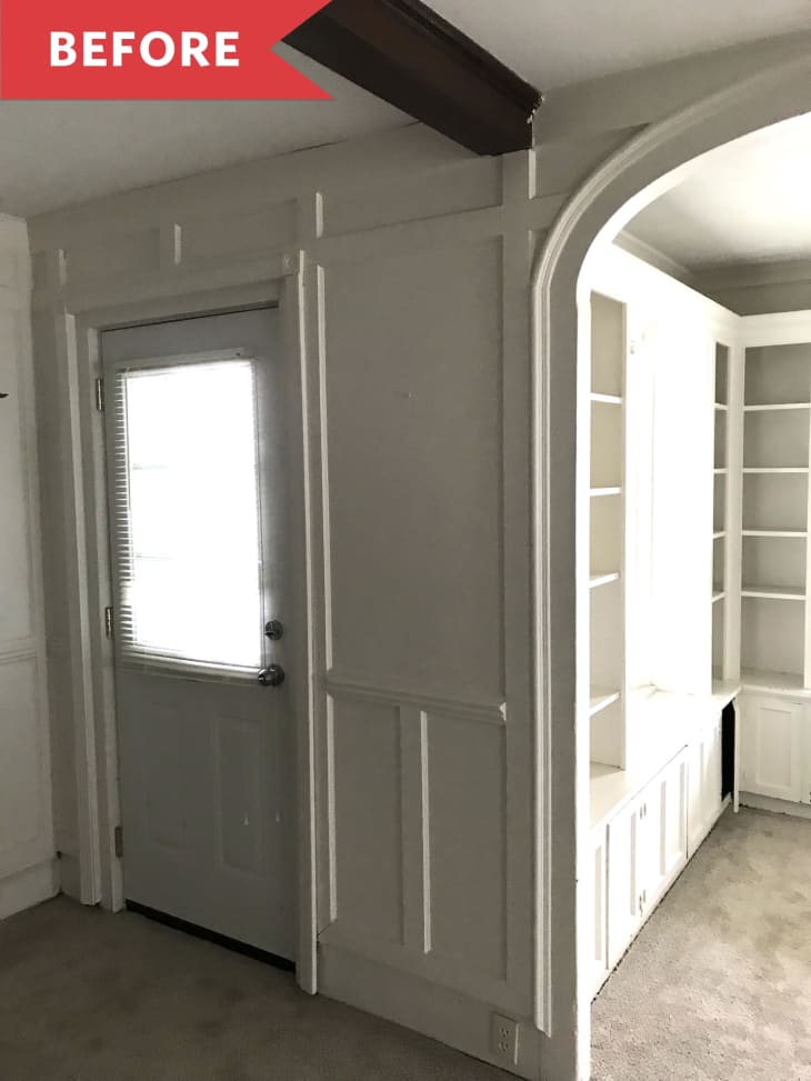 White paneled room with a door, built-in shelves, and an archway.