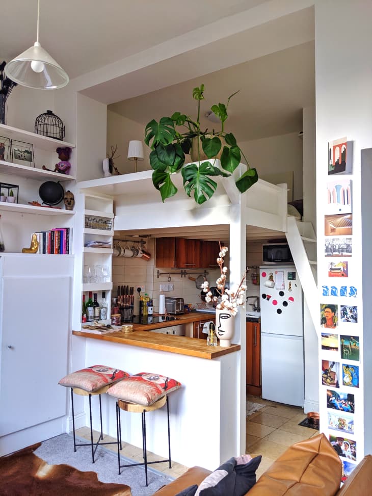 Loft-style kitchen with wooden countertops, bar stools, potted plant, and wall art.